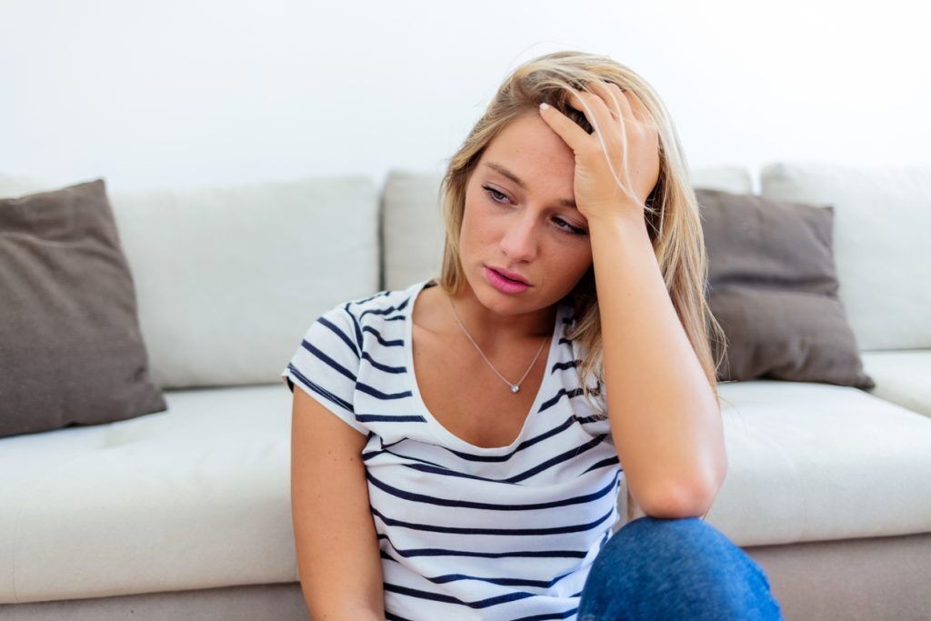 A stressed and tired woman is sitting in the living room.