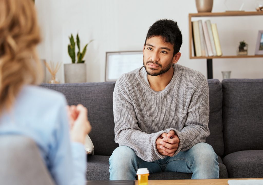 Finding the right therapist - Troubled man speaking with a mental health professional in a clinic.