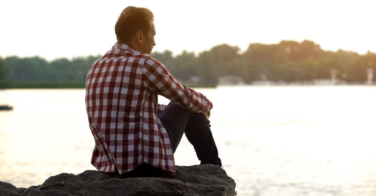 Man sitting calmly on a dock, representing rest and recovery from burnout